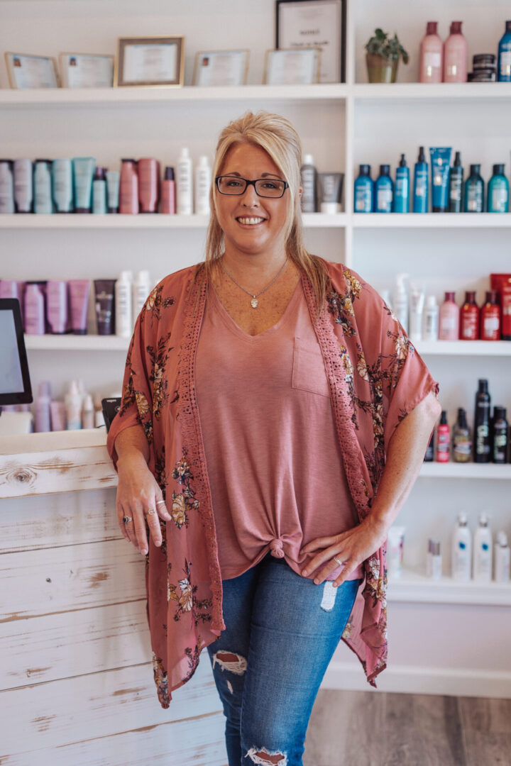 A woman standing in front of shelves with hair products.